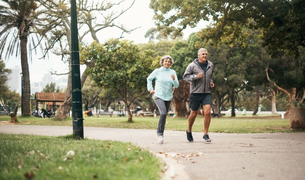 senior male and female running through a park
