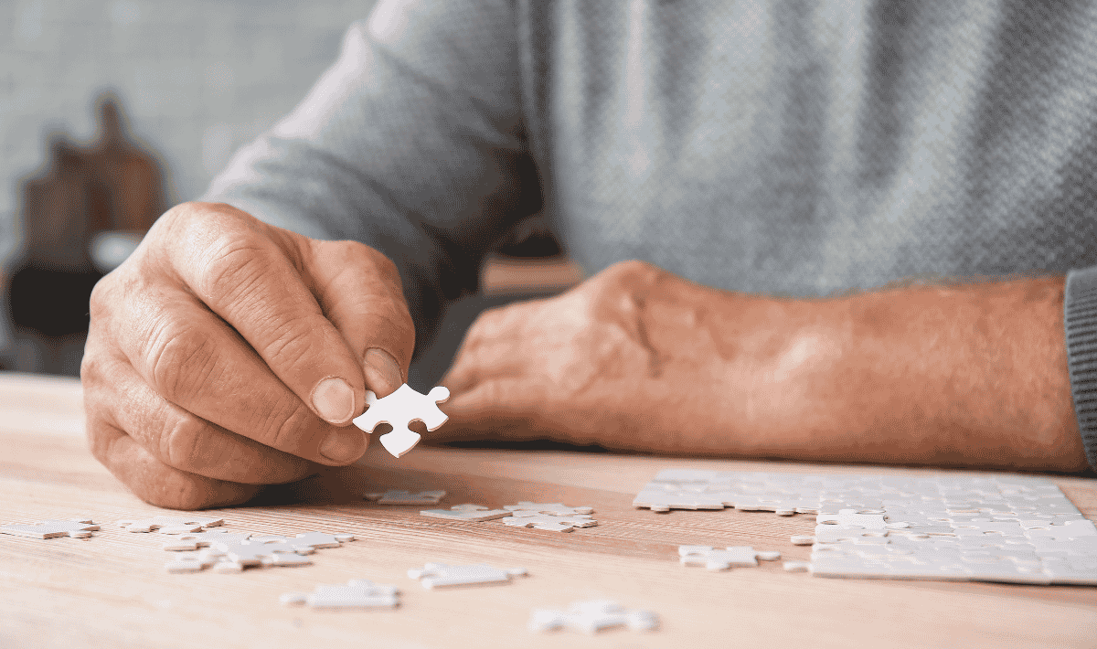 Older male holding jigsaw puzzle piece